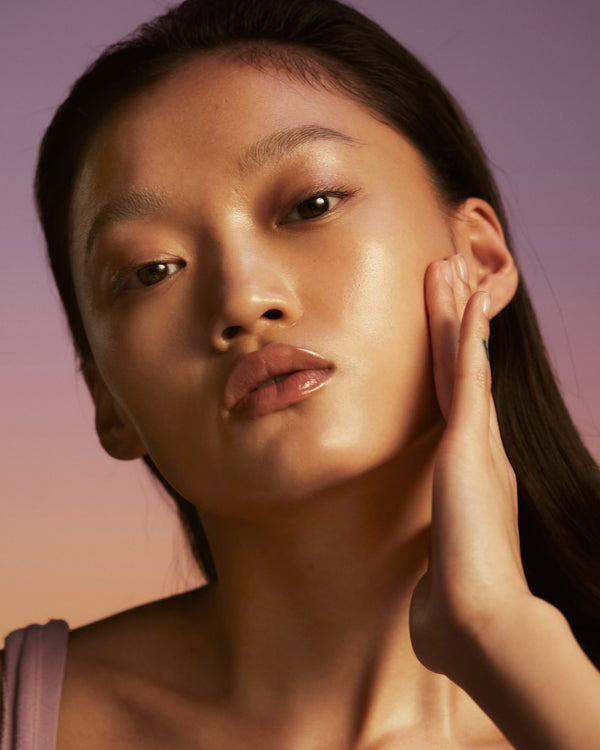 A close-up image of model applying Honey Infused Face Oil